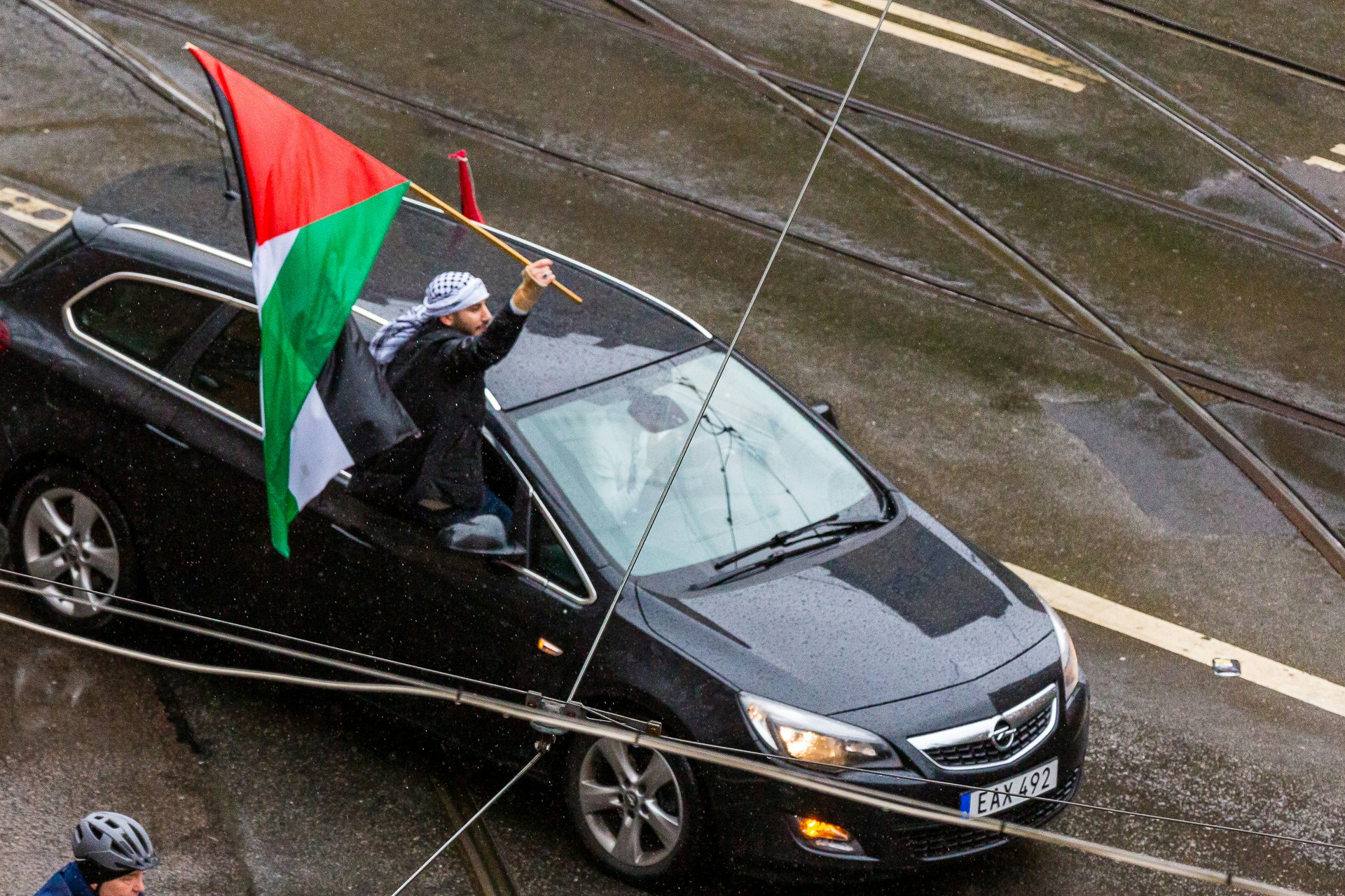 Protestor rides the windowsill as the car follows the convoy