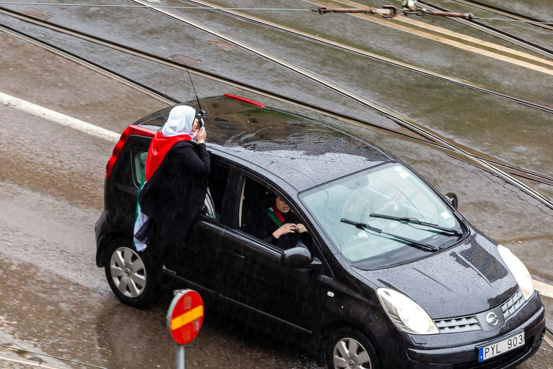 Balenced on the rear windowsill, a protestor narrates the situation