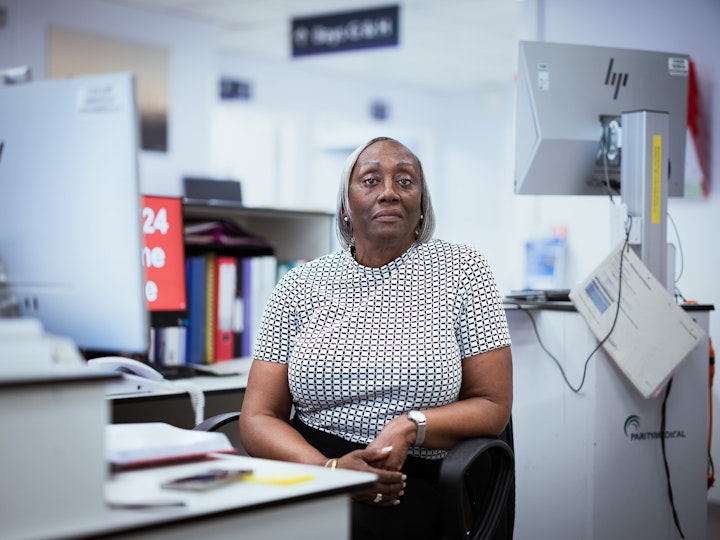 Open Britain x NHS Imperial Trust Collaboration - Alicia Weekes – ward administrator on Charles Pannett Ward, St Mary’s
Alicia Weekes was born in Barbados in 1957. Her mother came to work in the UK for Lyons Cakes as part of the Windrush Generation. Initially, Alicia didn’t see her mother for five years, however Alicia and her two brothers were reunited with her mother in London when Alicia was 10.
When she arrived Alicia cried a lot because she missed the freedom of Barbados. However, looking out the window, the fascination and novelty of seeing the milkman arrive everyday somehow helped. Aged 16, Alicia left school and trained as a chef. A variety of jobs followed before she joined the NHS in 1993.
Alicia has been a ward administrator for thirtee-one years, making appointments, discharging patients and helping the doctors. She loves helping people and solving problems. The NHS has changed a lot over this time, but Alicia has been a constant.