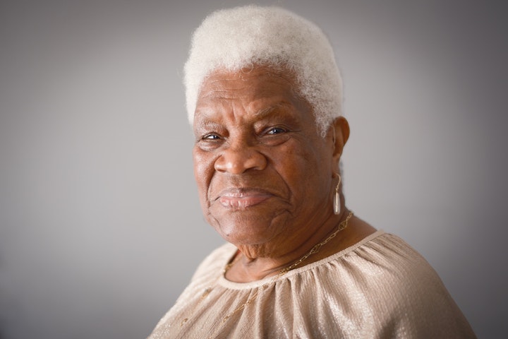 Open Britain: Portrait of a Diverse Nation - Maud Kathleen Albert is 92. She was born in Castries, St Lucia in September in 1931. Her parents followed a subsistence style of living: baking, farming, carpentry and keeping bees for their own needs. Maud left school at 15 to help her parents.
At the age of 30 her eldest sister ‘sent for her’ from the UK and in December 1960 she travelled on the Merchant Vessel Bianca leaving her two children behind. She moved in with her sister in West London and started working as a cleaner to cover her share of the rent.
It was December when she arrived, and she remembers being very angry with her sister for sending for her. By day she would have to walk hand in hand with a friend to find the station through the smog and streetlighting. And by night not able to go out after 6 because of the threat of the racist Teddy Boys. Fortunately, things started to change relatively soon after her arrival as her community started to fight back against Teddies and the unjust police.
When settled Maud sent for her kids and married Clayton, a fellow St. Lucian. Between them they parented eight children. Maud worked days as a cleaner whilst Clayton looked after the kids before heading off on the nightshift, when Maud would take over. Maud was accompanied by her daughter Linda when we met who remembered a happy busy house in which the ‘shift parenting’ really worked.
Social worker, clinical psychologist, nursery school owner, psychotherapist, social worker for the hearing impaired and mental health administrator are just some of the jobs Maud’s children are doing. Who knows what the 21 grandchildren and 17 great grandchildren (and counting) will go on to give.