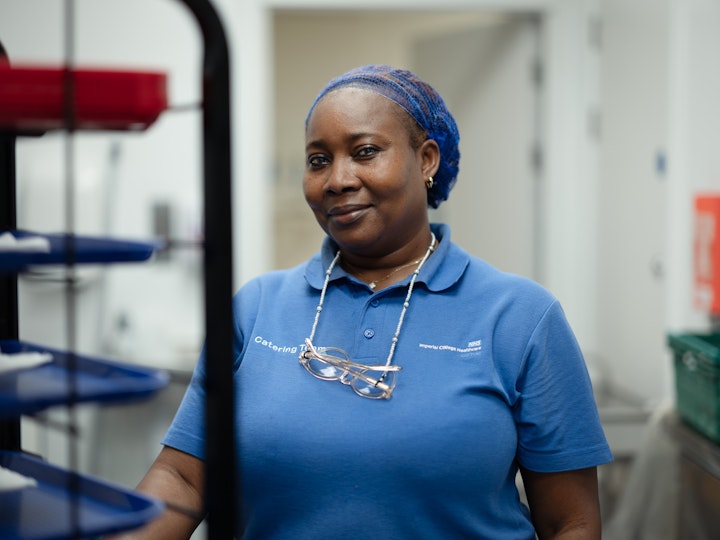 Open Britain x NHS Imperial Trust Collaboration - Chinenye Osinowo, Catering Assistant in Oncology Ward, Charing Cross
Chinenye Osinowo studied journalism back in Nigerian and worked as a reporter at a national newspaper in Lagos. She packed it in to be a mother. Her three children came to university here to study robotics and engineering, software engineering and Artificial Intelligence and physics, so Chinenye followed.
When Chinenye finished secondary school in Nigeria she went to work with her aunt as an assistant in a maternity home, where she developed an interest in caring.
Chinenye has been a catering assistant for 2 years, she looks after the patients, taking care of their nutritional needs, maintaining the cleanliness of the kitchen and the ward and the patients’ environments.
The patients on her ward tend to be there for long period and are in end of life and Chinenye enjoys the bond he develops with them.
She misses the food, the culture and like to many international staff… the climate.
