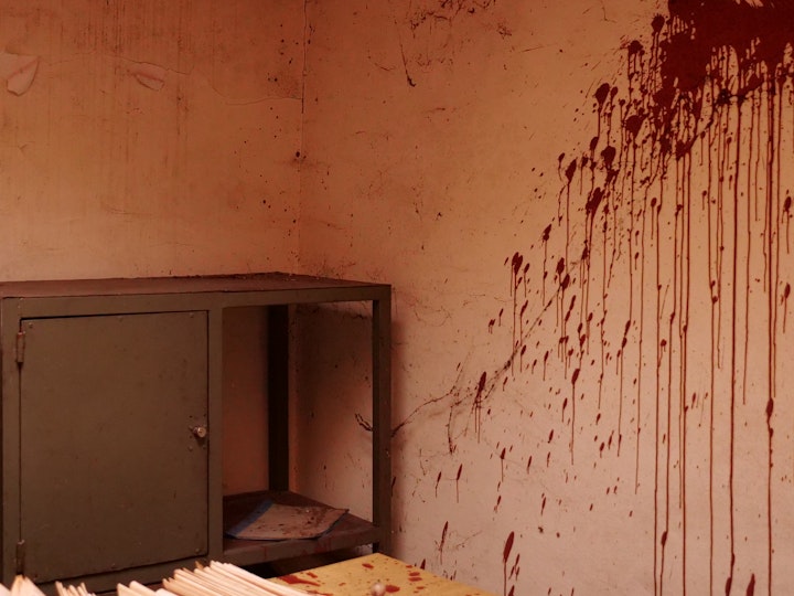 A dark red splash stains the wall of a ransacked office in an abandoned factory