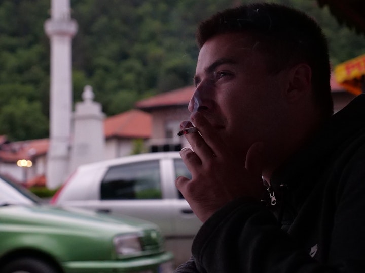 Batan smoking a cigarette in front of Salko's bakery