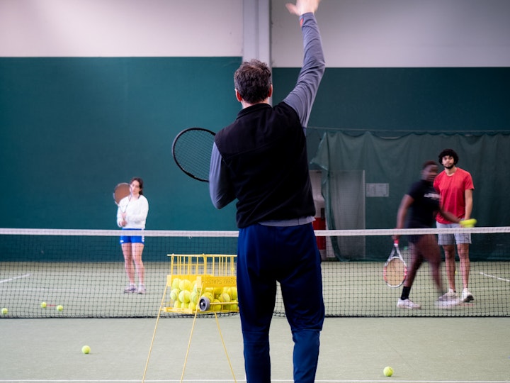 Le professeur de tennis Cyrille Monet pendant un exercice de smash avec des étudiants de L2, en cours pratique