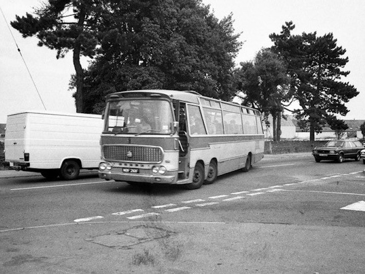 From the Alan Jordan Collection (Bob's nephew), this photograph captures the end of the afternoon shift at Newman Industries. Part of the Newman’s afternoon mass departure is Bedford VAL/Duple Viceroy NDF 210F.
The exit to the car-park stands where the junction of Eggshill Lane and Station Road and is taken from outside the old Co-Op (now Tesco Express). The site of the car park is now Mow Barton.
At the time (early 1980’s), Newmans, like many other major employers, operated a network of bus services exclusively to provide their employees transport to/from work. The end of the shift would often see the car park empty of all cars and numerous buses and coaches within a 10-15 minute period!