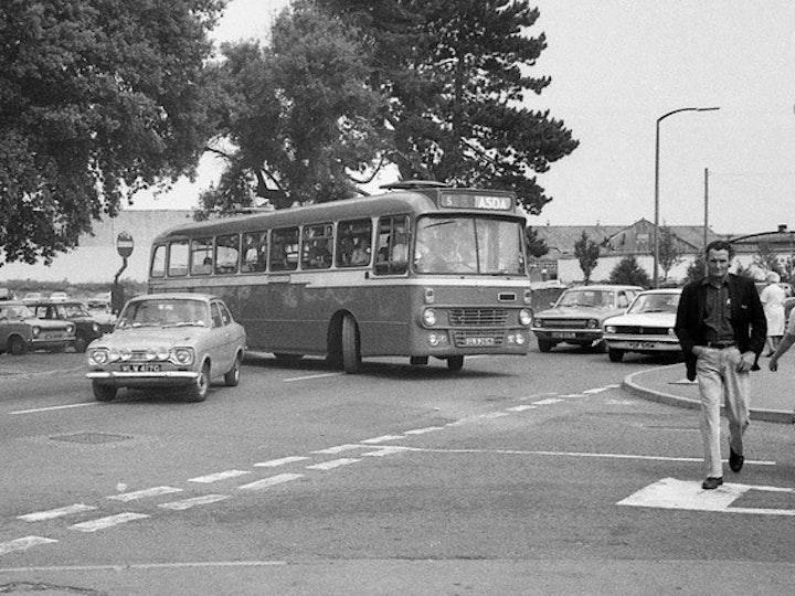 From the Alan Jordan Collection (Bob's nephew), this photograph captures the end of the afternoon shift at Newman Industries. The exit to the car-park stands where the junction of Eggshill Lane and Station Road and is taken from outside the old Co-Op (now Tesco Express). The site of the car park is now Mow Barton.
At the time (early 1980’s), Newmans, like many other major employers, operated a network of bus services exclusively to provide their employees transport to/from work. The end of the shift would often see the car park empty of all cars and numerous buses and coaches within a 10-15 minute period! 
This particular afternoon sees many private cars, including Ford Escort MK1’s, a Triumph Herald and Talbot Avenger PDF515M with Eagle Coaches Ford/Alexander GLS 261N exiting the car park on one such route. The bus was new to Scottish operator Alexander (Midland) in October 1974 - seen here in Yate less than ten years afterwards now owned by Eagle - an operator still going strong in 2021!