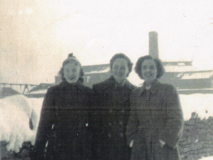 Photograph of three ladies on what is presumed to be Station Road in Yate with the National Concrete Slab Factory in the background including the elevated tramway that transported stone from the nearby quarry to the south west of the factory.
