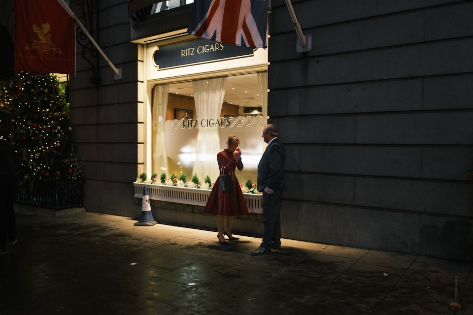 Street Folio II - A woman lights a cigarette outside the Ritz hotel on Piccadilly, London