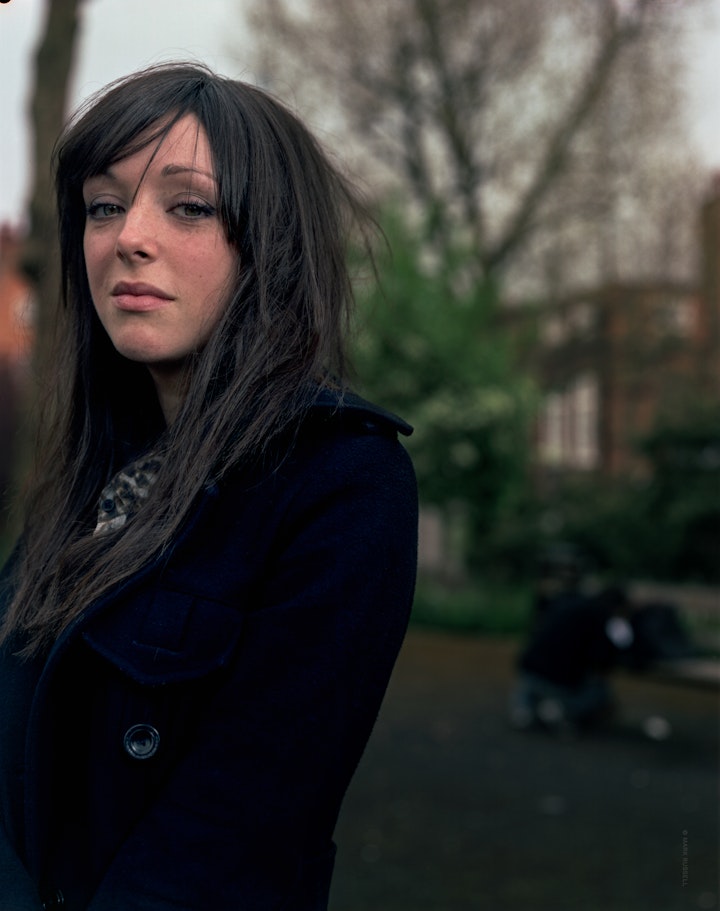 An outdoor portrait of Kirsty to the left of the frame wearing black and looking directly at the camera.