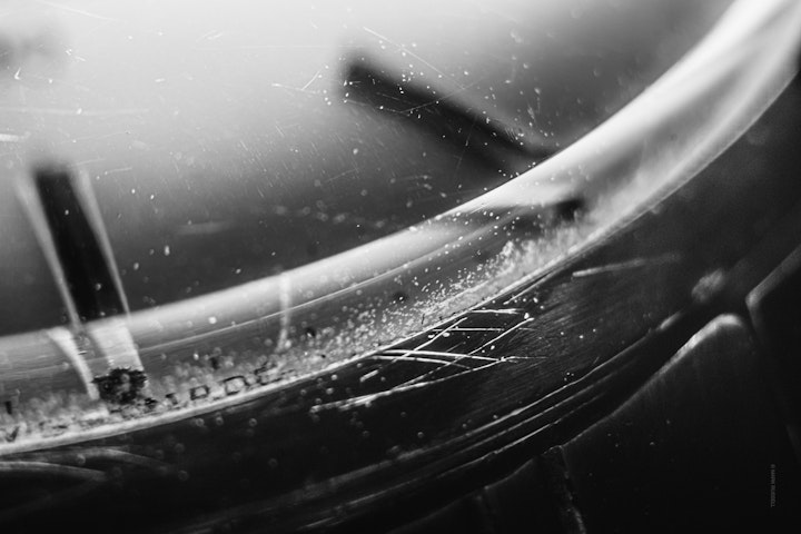 Macro super-closeup of a watch dial and crystal in black and white.
