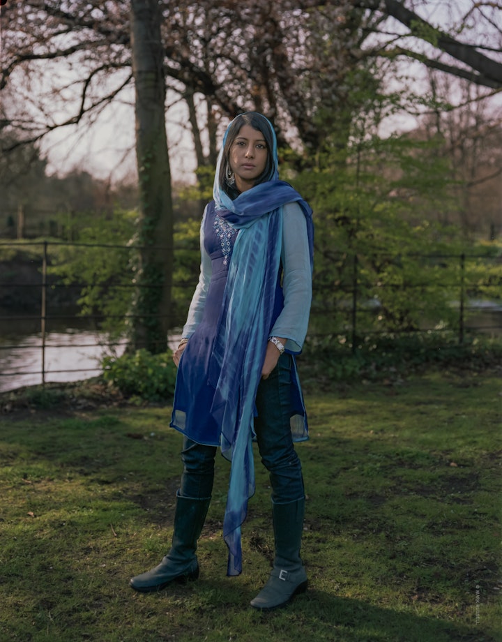 A portrait of Yasmin, standing in the gardens of Morden Hall in south London wearing a blue headscarf.