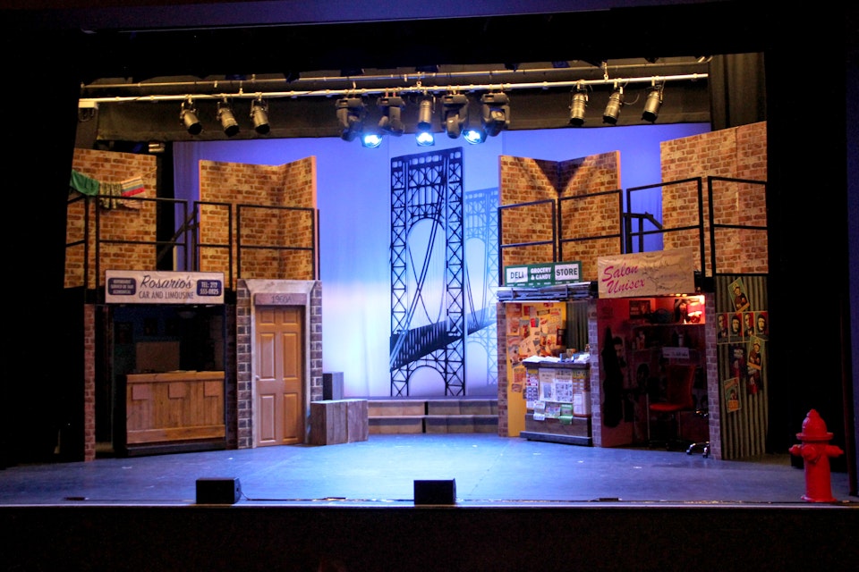 In the Heights - The whole set. The store fronts and balconies above were set on steel deck. The George Washington bridge was custom printed on a white vinyl strip and placed against a white cyclorama.