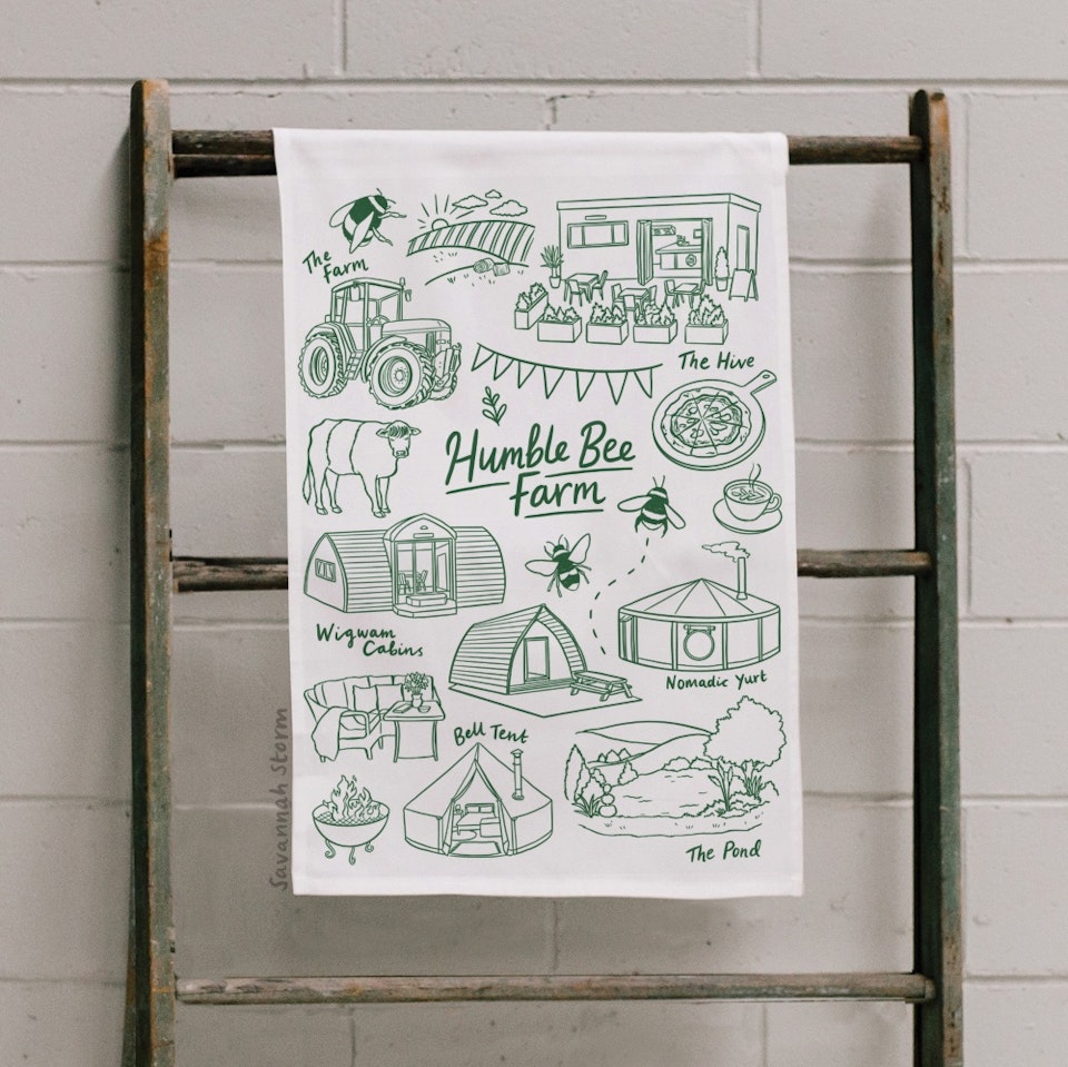 Humble Bee Farm - A tea towel screen printed with an illustrated farm design, including a tractor, tents and cabins, farmyard animals, and bees.