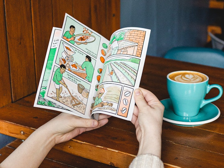 Just a Coffee, please - A comic book open on a page showing illustrations of how coffee beans are sorted, de-pulped and dried out before roasting. Coffee plantation workers spread the beans out onto long drying tables in the sun to slowly dry them out.