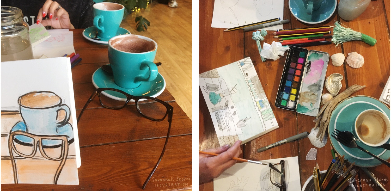 Sketchbook spreads at a drawing workshop, one is being held up to show what was drawn, the other is a top down view of a table with a sketchbook surrounded by art materials, paints, an empty coffee cup and some shells.