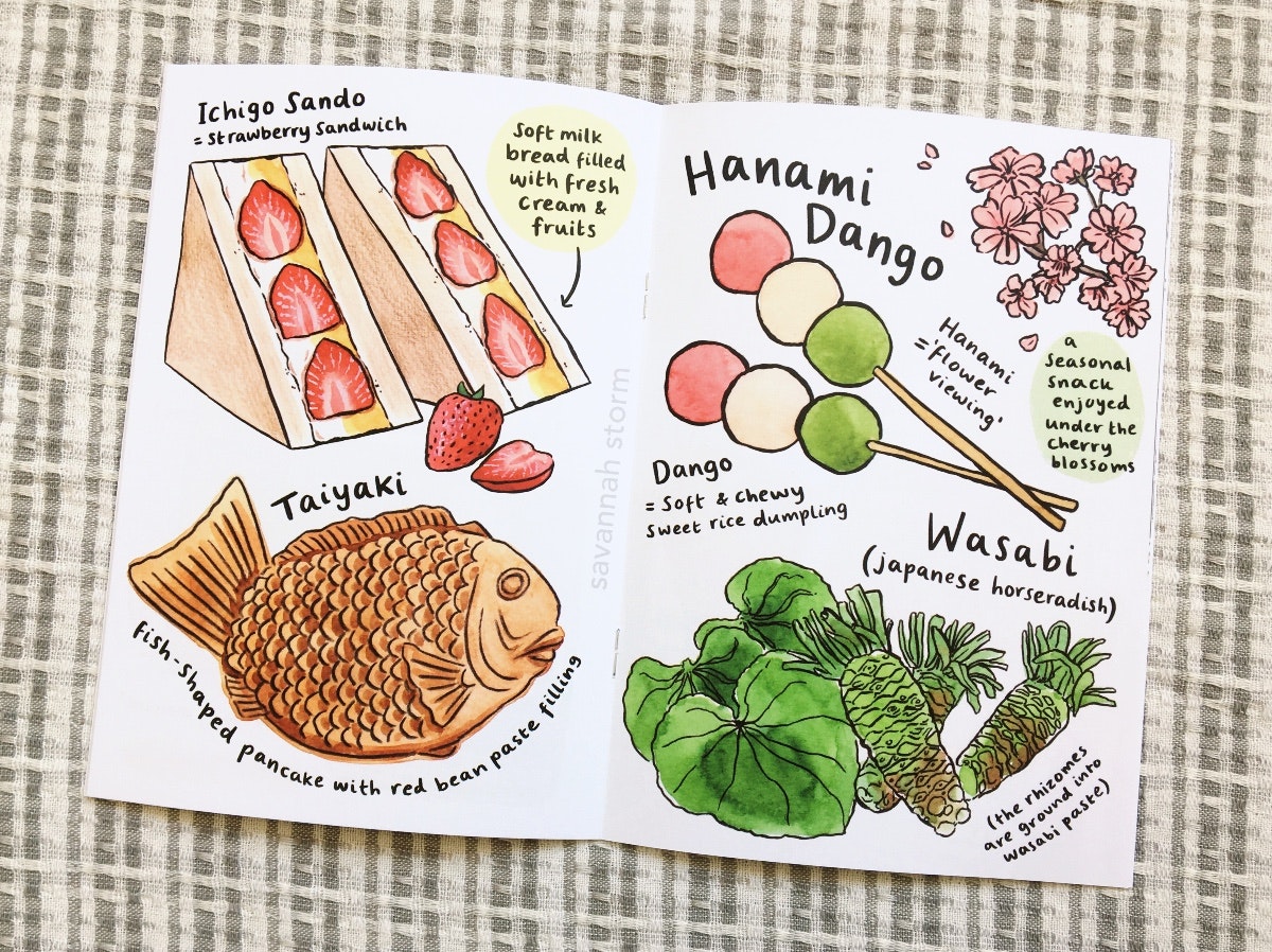 An illustrated zine about Japan, open on a page showing foods including a strawberry sandwich, a taiyaki, some hanami dango and some wasabi.