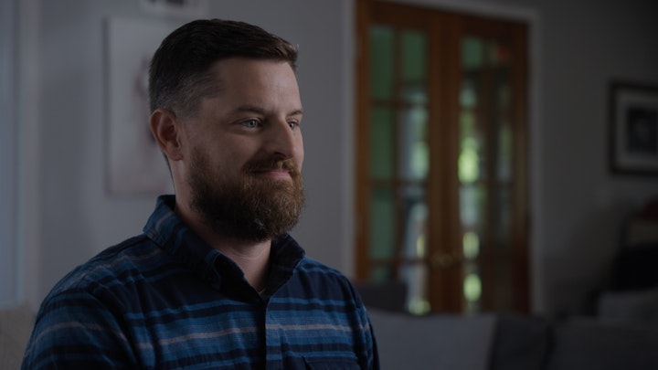 Man waiting in living room smiling in peaceful lighting