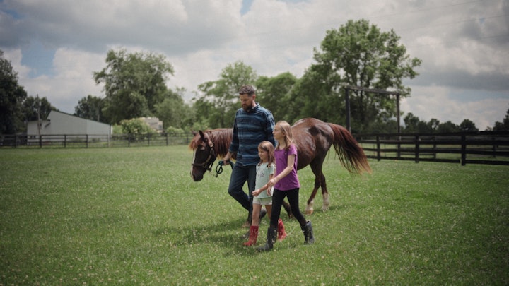 father walking with daughters and horse on rural farm fences and open field