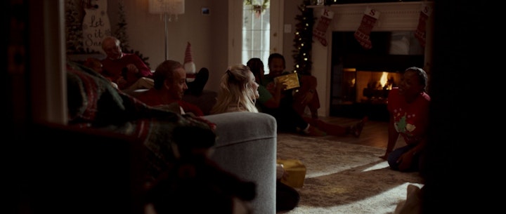 A diverse group of individuals sitting on the floor, captivated by a beautifully decorated Christmas tree with gifts, celebrating