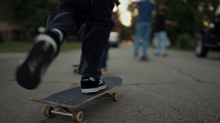 close up of feet on a skateboard going fast down a neighborhood street