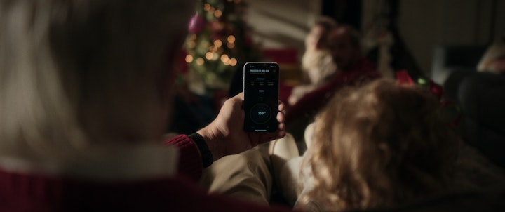 A man holding a smart phone in front of a christmas tree.