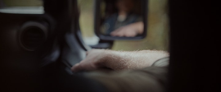 A man driving a car, focused on the road ahead while glancing out the window.