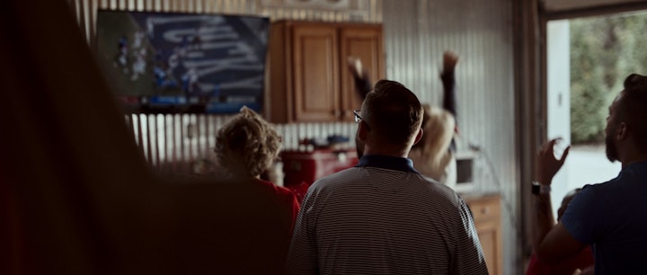 A lively room filled with people watching a football game together, cheering and enjoying the excitement.