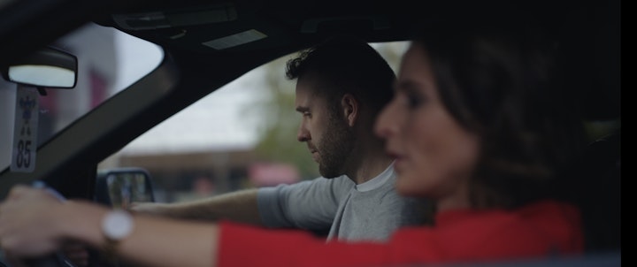 man and woman in car after fight, crying, looking sad while parked in a lot
