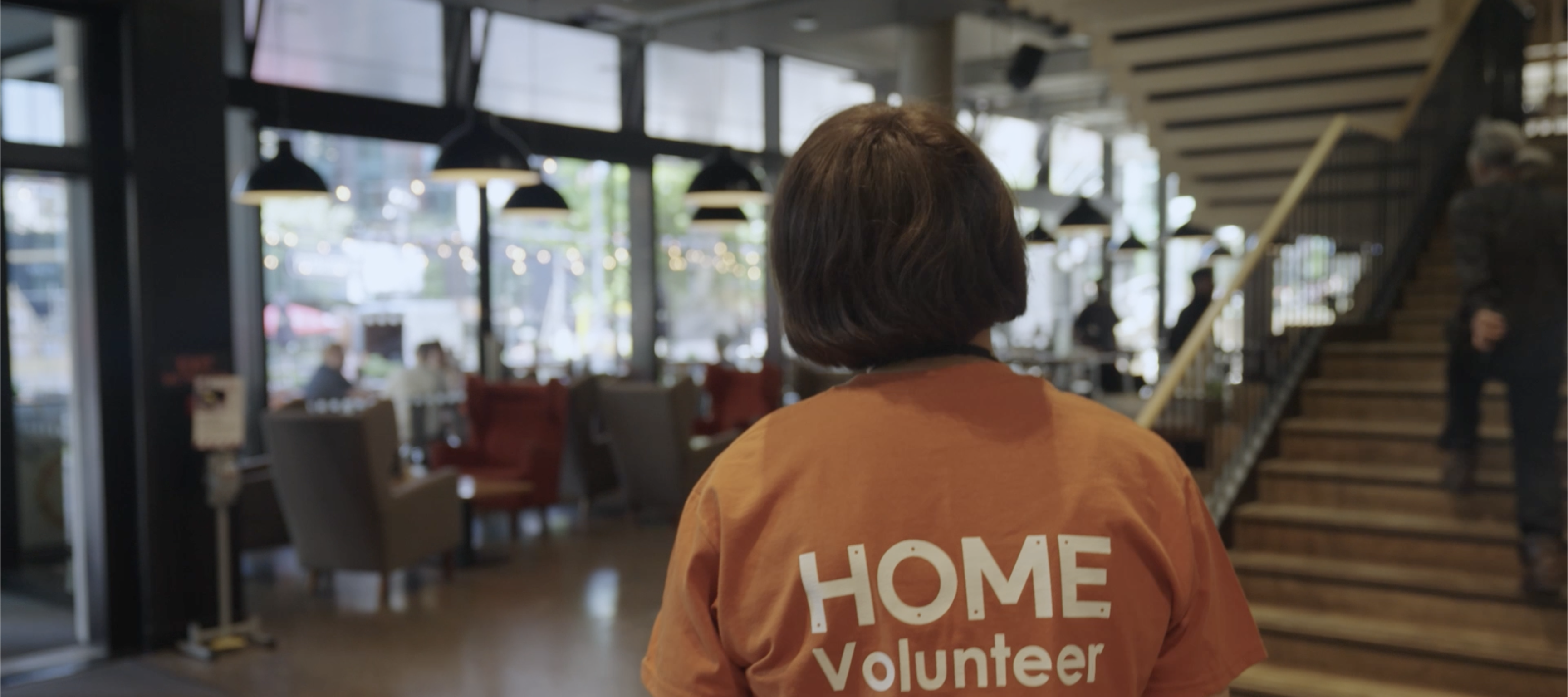 A young person in an orange T-shirt with HOME Volunteer written on it.