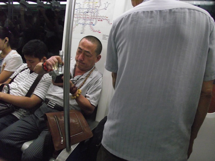 Stone gambler examines purchase for translucency on Beijing Metro, 2013.